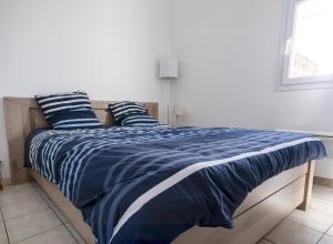 a bedroom with a bed with blue and white sheets at maison 300m mer à Brétignolles-sur-Mer (La Parée)- Calme in Brétignolles-sur-Mer