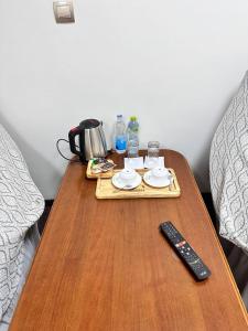 einen Tisch mit Fernbedienung und ein Tablett mit Getränken darauf in der Unterkunft ADMIRAL in Termiz