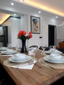 a dining room table with white plates and a vase with red flowers at Villa Bağ Tepesi in Fethiye