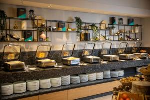 a buffet line with plates and pans on a counter at Mona Plaza Zlatibor in Zlatibor +47 photos
