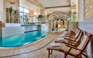 a pool with a row of chairs next to a swimming pool at Corinthia St George's Bay in St. Julianʼs