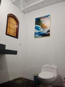 Krui的住宿－Rumah Nalu surf camp，一间带卫生间的浴室和墙上的照片
