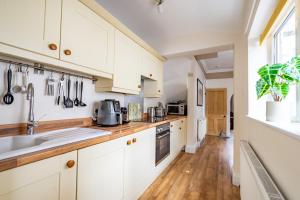 a kitchen with white cabinets and a wooden floor at Buckingham Townhouse in York