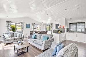 a living room with two couches and a kitchen at Foxglove Lodge, 31 Roadford Lake Lodges in Lifton