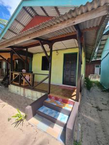 een huis met een veranda met een deur en een trap bij Rainbow Tioman Cottage in Kampong Juara
