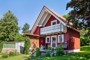 a red house with a balcony and a yard at Naturhäusle Oberschwaben in Ebersbach-Musbach
