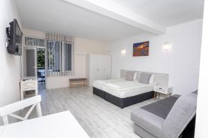 a bedroom with a bed and a couch and a tv at Guest rooms and apartments Desi in Balchik