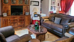 uma sala de estar com sofás de couro e uma televisão em Casa Alegre Guesthouse em Southbroom