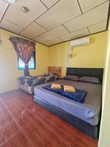 een kamer met 2 bedden en een raam bij Rainbow Tioman Cottage in Kampong Juara