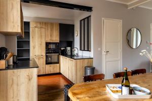 a kitchen with wooden cabinets and a table with a bottle of wine at Villa Durant in Saint Malo