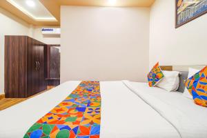 um quarto com uma cama branca e um cobertor colorido em FabHotel Roadside Inn em Naksalbāri