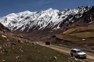 a truck driving down a road in front of a snow covered mountain at Guest House Shirin in Barskoon