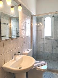 W łazience znajduje się umywalka, toaleta i lustro. w obiekcie Angelica Studios and Apartments w mieście Agia Marina Nea Kydonias