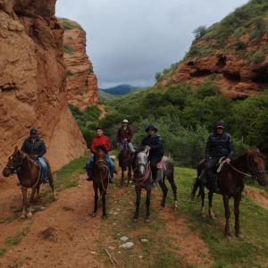 a group of people riding horses on a dirt road at Guest House Shirin in Barskoon