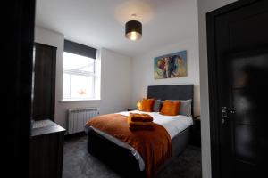 a bedroom with a bed with orange pillows and a window at Victoria Apartments in Skegness