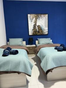 - 2 lits dans une chambre avec un mur bleu dans l'établissement Large Penthouse In Cenrtal Area, à Il-Gżira