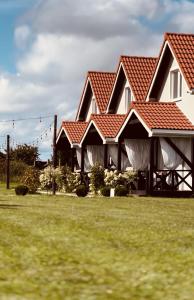 ein Haus mit roten Dächern auf einem grünen Feld in der Unterkunft Goose Home and Garden in Łeba