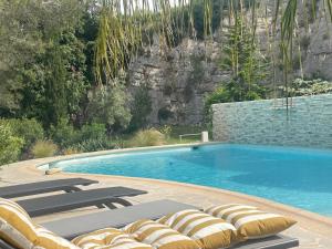 a swimming pool with lounge chairs next to a mountain at La villa des Carriers - maison avec piscine, 10 min mer in Roquefort-les-Pins