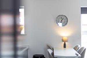 a table with chairs and a clock on the wall at Victoria Apartments in Skegness