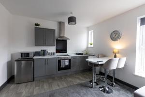 una cocina con armarios grises y una mesa. en Victoria Apartments en Skegness