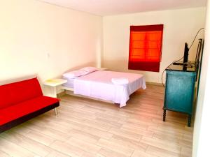 ein Schlafzimmer mit einem Bett und einem roten Sofa in der Unterkunft Acogedoras Casas de campo en Cieneguilla in Cieneguilla