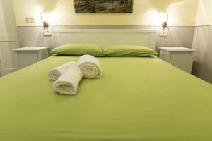 a bedroom with a green bed with towels on it at Petrarussa Dimora Storica in Morciano di Leuca