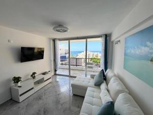 Una sala de estar con un sofá blanco y una ventana grande. en Luxury Ocean View Apartment 6th floor, en Los Cristianos