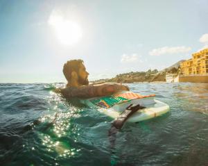 a man laying on a surfboard in the water at Corinthia St George's Bay in St. Julianʼs