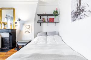 Habitación blanca con cama y espejo en GuestReady - Peaceful Getaway near Belleville, en París