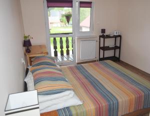 a bedroom with a bed with a striped blanket and a window at Nad Krolówką in Ustrzyki Dolne