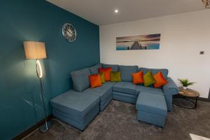 a living room with a blue couch with colorful pillows at Victoria Apartments in Skegness