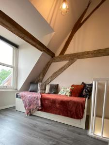 a bed in a attic with a red blanket at Luxe en ruim appartement in Rijksmonument in Vianen