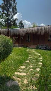 een huis met een grasdak en een pad bij The Mudhouse Marayoor in Munnar