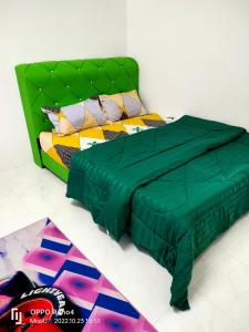 1 cama con edredón verde en una habitación en Raihan Homestay Seri Iskandar Perak Near UTP UITM en Seri Iskandar