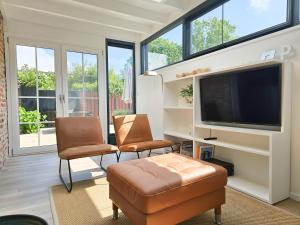 a living room with a flat screen tv and two chairs at Vrijstaand vakantiehuis AK14 Aagtekerke in Aagtekerke