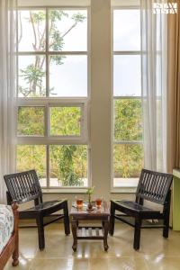 two chairs and a table in a room with windows at The Pastel Courtyard with Pvt Pool & Garden at Jaipur by StayVista in Jaipur