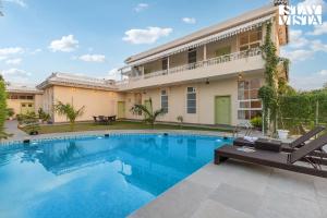 a villa with a swimming pool in front of a house at The Pastel Courtyard with Pvt Pool & Garden at Jaipur by StayVista in Jaipur