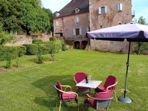 a table with chairs and an umbrella in a yard at Manoir du Boscau, Gilles del Bosc in Prudhomat