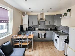 cocina con armarios grises, mesa y sillas en Lovely 3 bed apartment in the City of London, en Londres