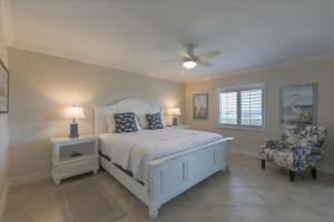 a bedroom with a bed with a ceiling fan and a chair at SANDPIPER BEACH 205 in Sanibel