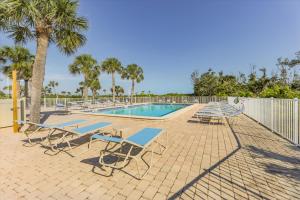 a swimming pool with lounge chairs and a fence at SANDPIPER BEACH 205 in Sanibel
