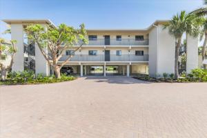 a large white building with palm trees in front of it at SANDPIPER BEACH 205 in Sanibel