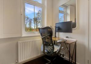 a desk with a chair in a room with a window at Stylish, business traveller friendly apartment, with free parking and Netflix in Farnborough