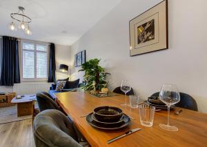 mesa de comedor con sillas y copas de vino en Stylish, business traveller friendly apartment, with free parking and Netflix en Farnborough