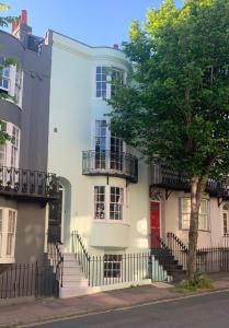 a white house with a red door and a tree at Lovely Flat Ensuite Bathroom Private Courtyard in Brighton & Hove