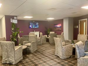 a waiting room with chairs and a table and a monitor at Britannia Edinburgh Hotel in Edinburgh