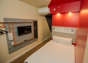 Cette petite chambre comprend un lit et une télévision. dans l'établissement IBIS BUDGET CAPAO Bonito, à Capão Bonito