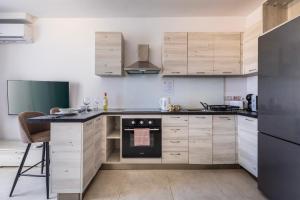 een keuken met houten kasten en een fornuis met oven bij Dorris's Apartment 5 min walk from St Julians in San Ġwann