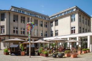 a large building with tables and umbrellas in front of it at Hotel Aquino Berlin in Berlin