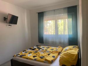 1 dormitorio con 1 cama con edredón amarillo y ventana en Mirabella Apartman Siófok en Siófok